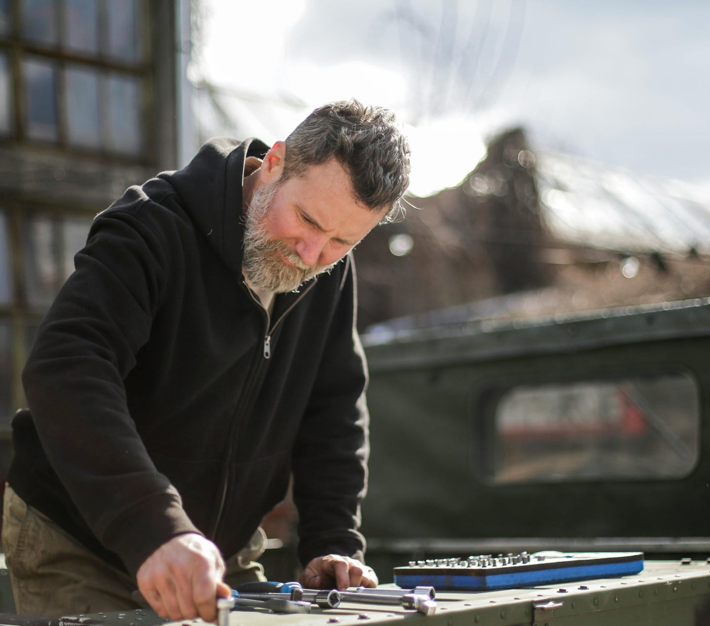 Adult mechanic working with metal details of car near garage
